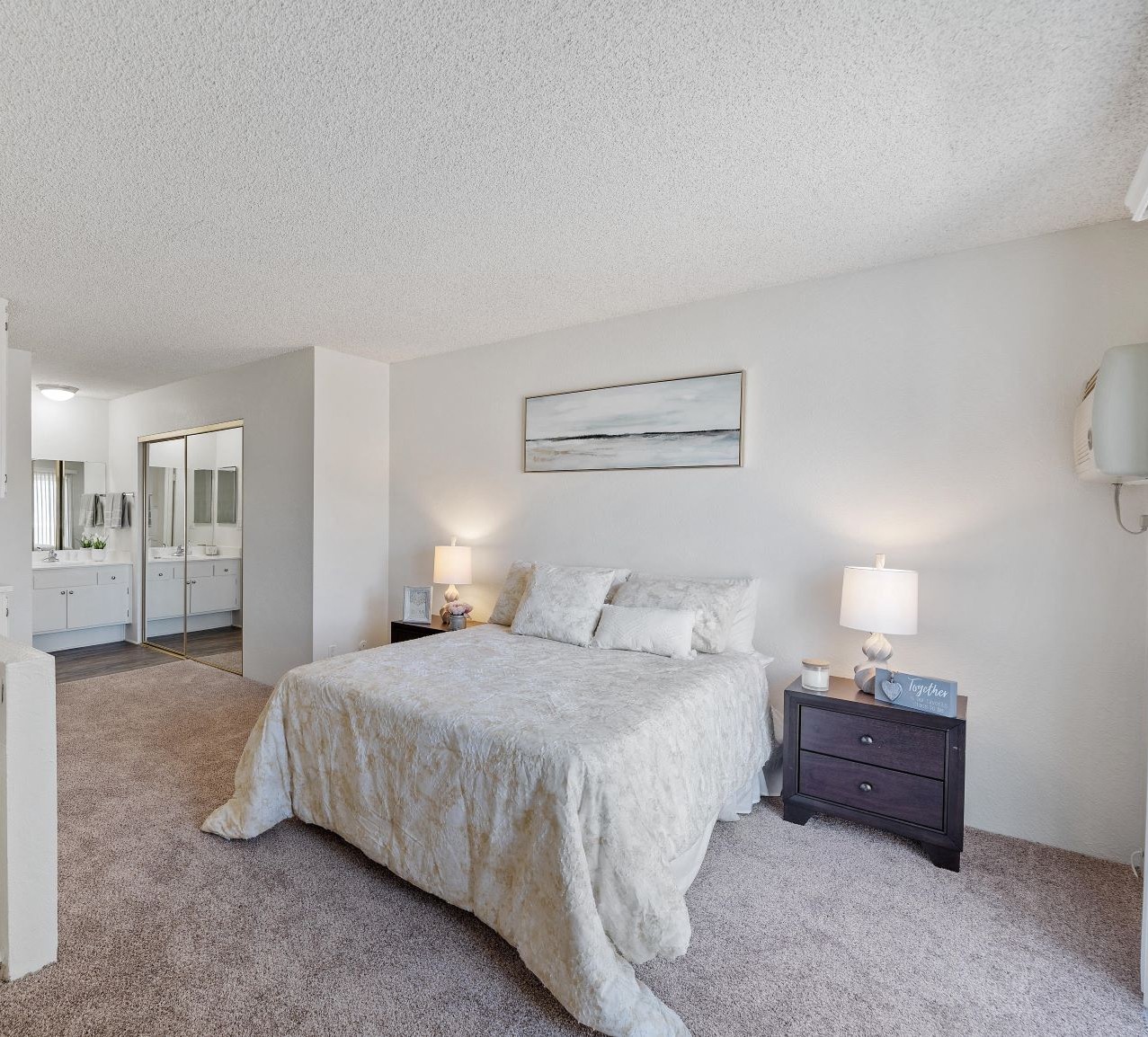 A bedroom with a large bed and a nightstand with two lamps.