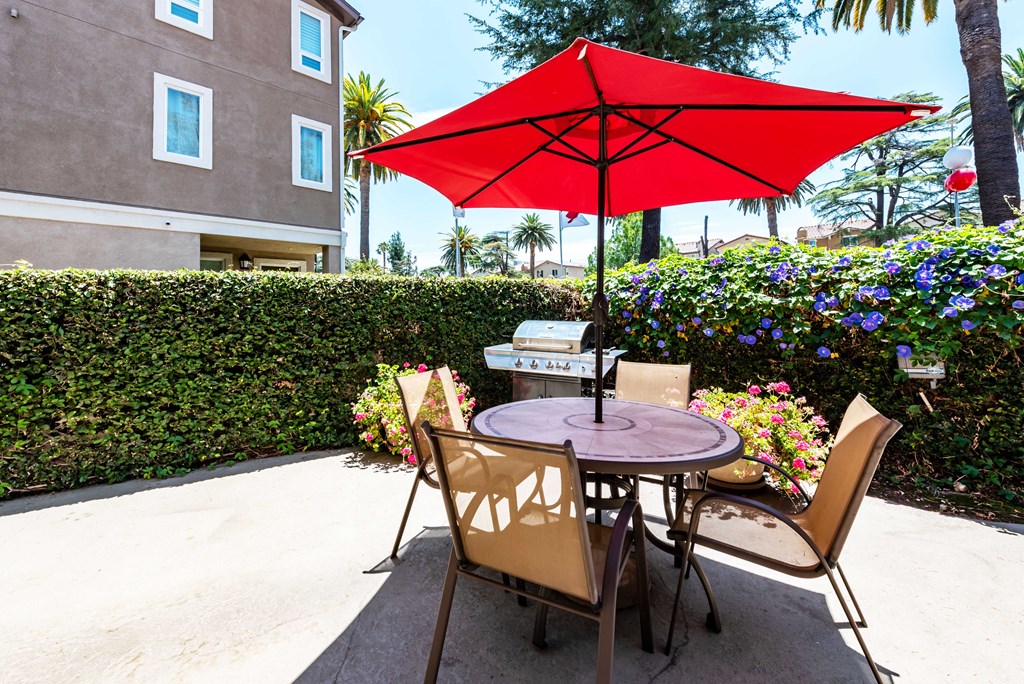 a patio with a table and chairs under a red umbrella