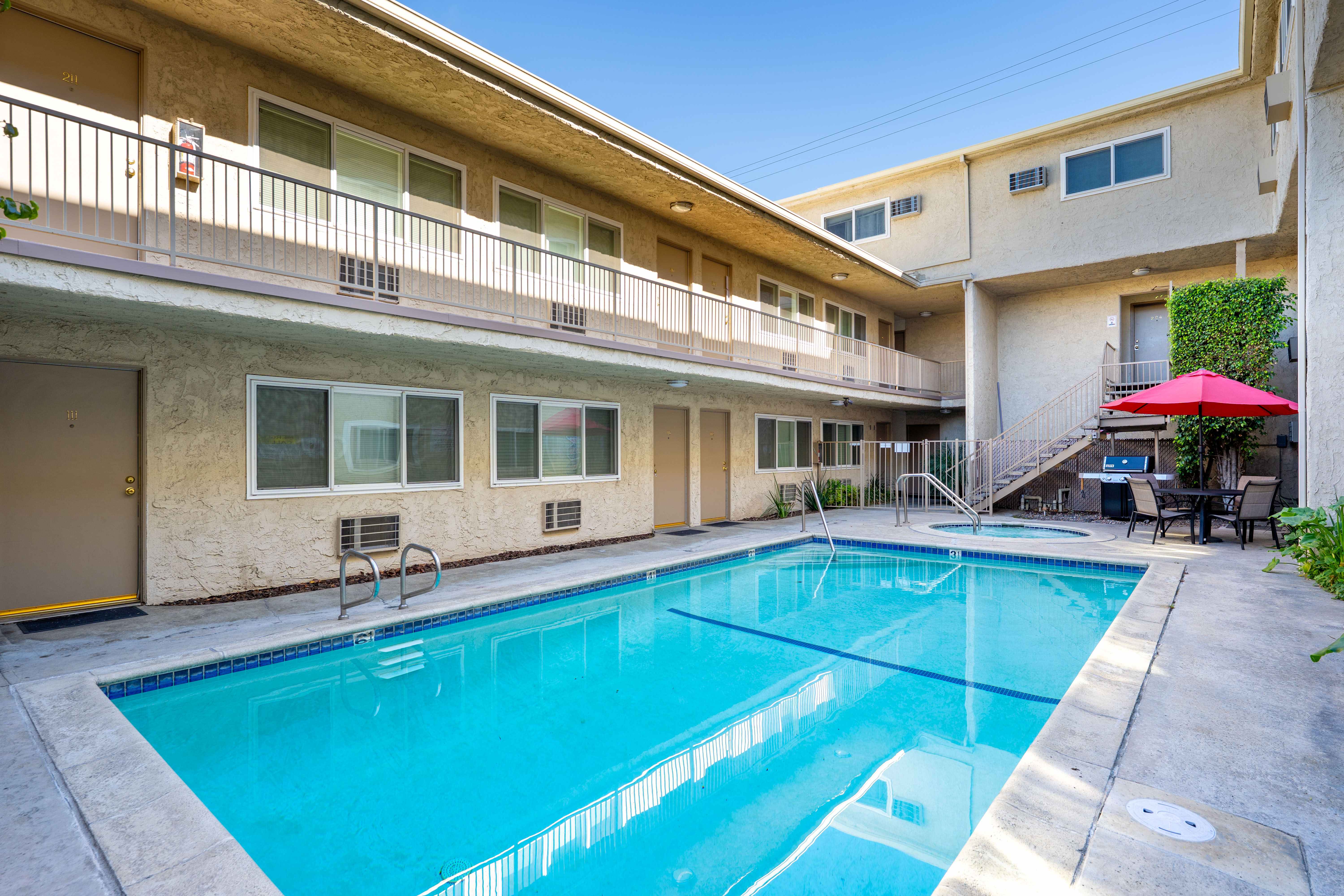 A rectangular sparkling blue swimming pool at Esplanade apartments surrounded by outdoor walkways.
