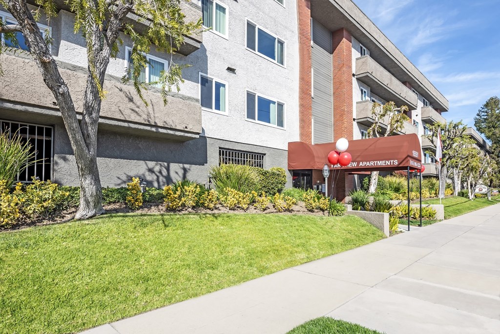a sidewalk in front of an apartment building with a red awning