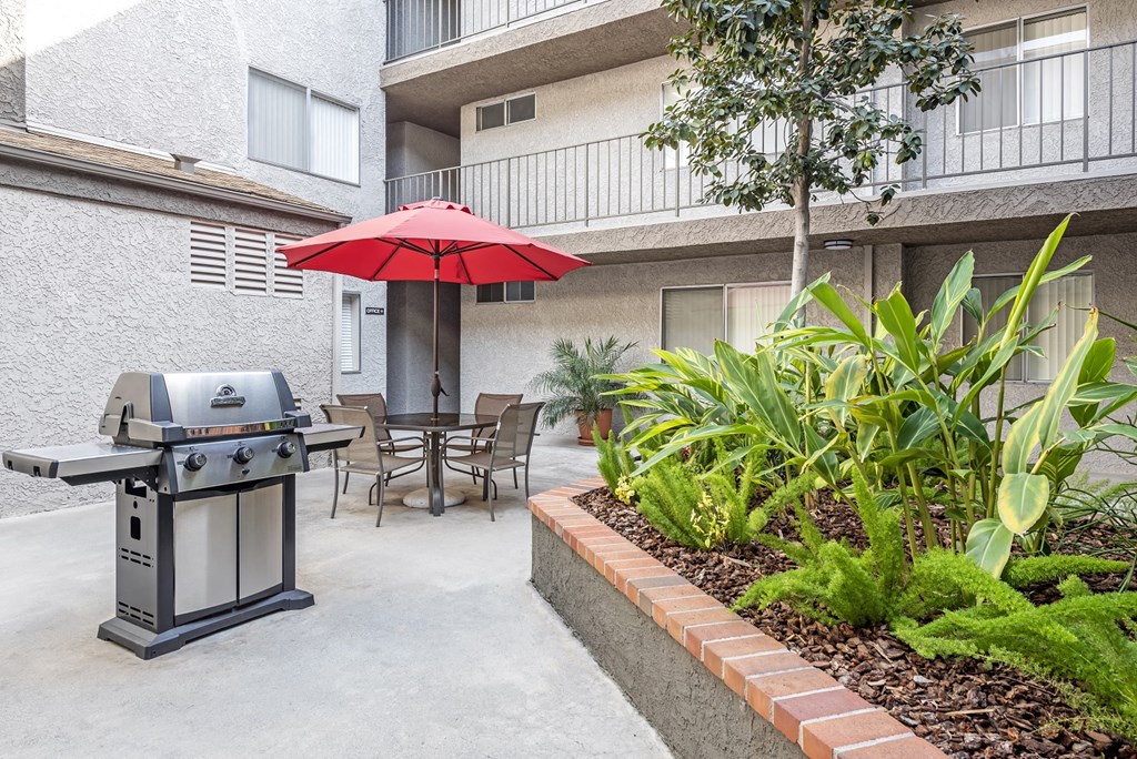 a patio with an umbrella and a grill