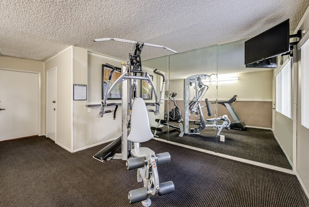 a gym with exercise equipment and a tv on the wall