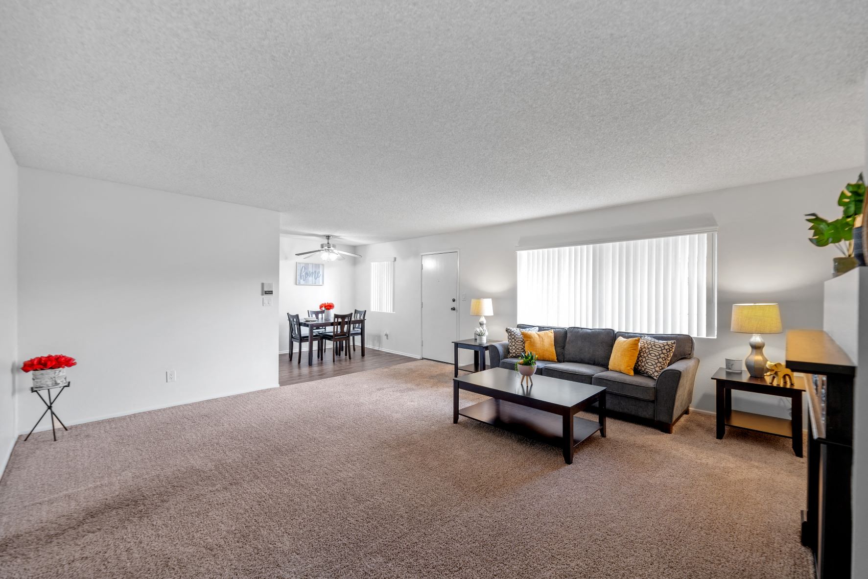 Spacious and cozy living room at the Hallmark Apartment in Sherman Oaks overlooking the dining room with plank flooring and a dining table with accessories