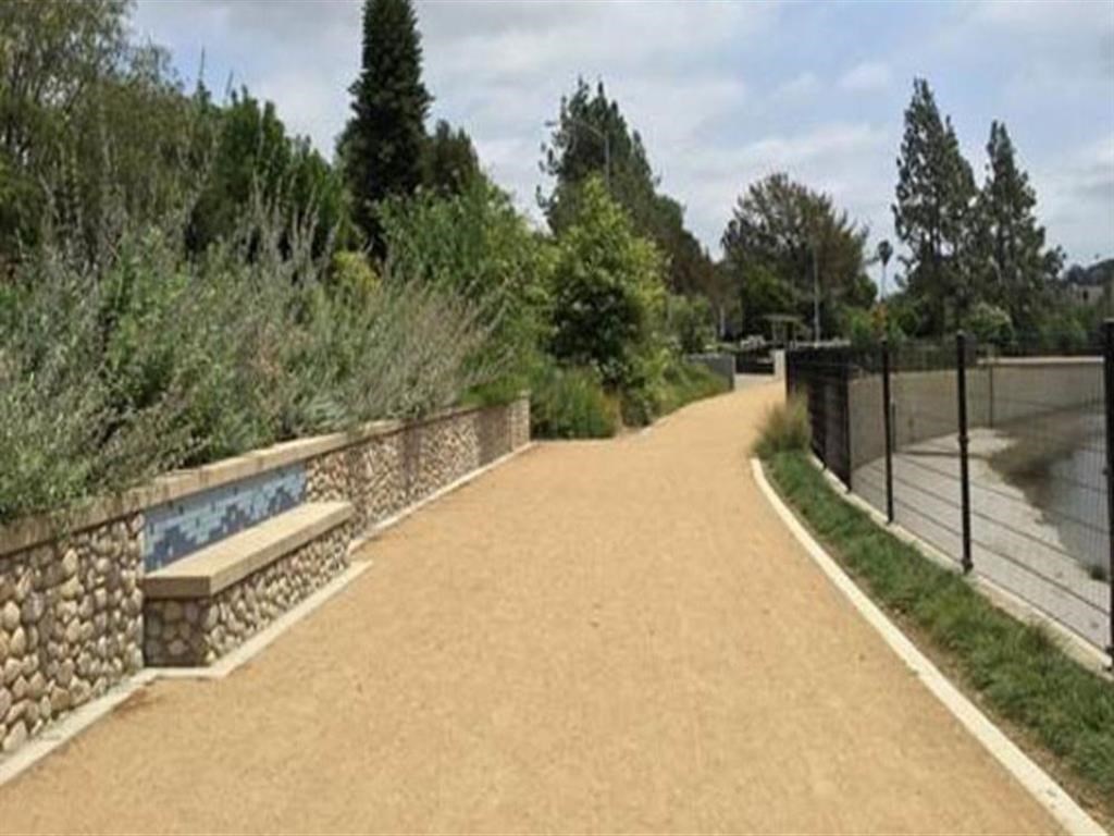 a path with a bench next to a fence