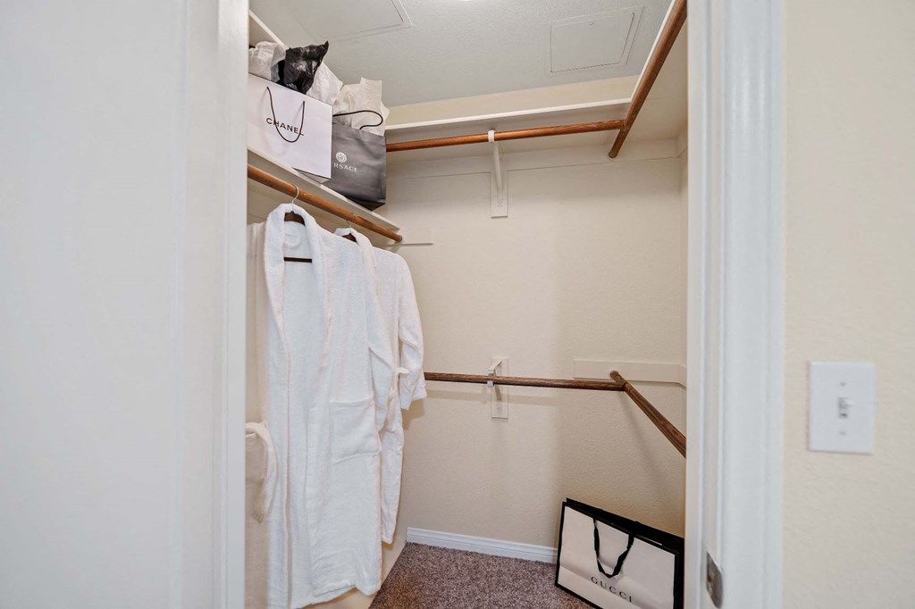 a walk in closet with robes and a bag on a rack