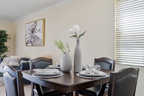 a dining room table with three vases with flowers on it