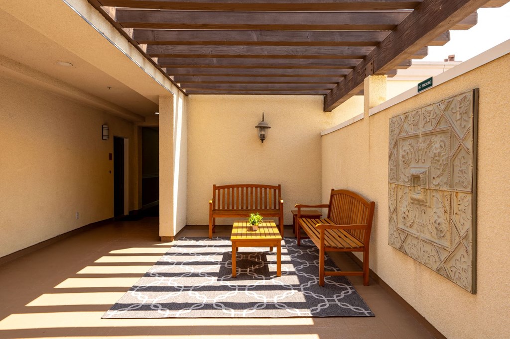 a covered patio with two wooden chairs and a coffee table