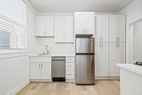 A kitchen with white cabinets and a stainless steel refrigerator.