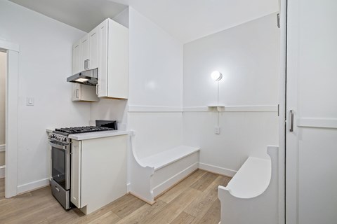 A white kitchen with a stove and a bench.