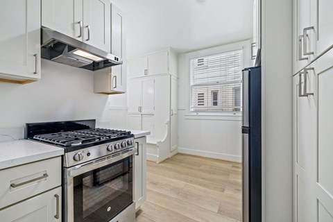 A kitchen with a stove top oven and a refrigerator.