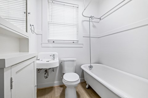 A white bathroom with a toilet, sink, and bathtub.
