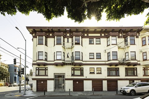 A white building with brown trim and a balcony on the second floor.