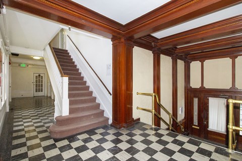 A hallway with a staircase and a checkered floor.