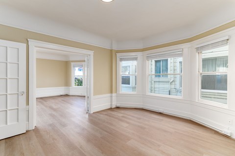 A room with a white door and a window with white curtains.