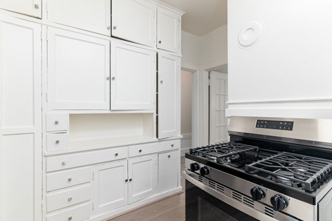 A kitchen with white cabinets and a stove top oven.