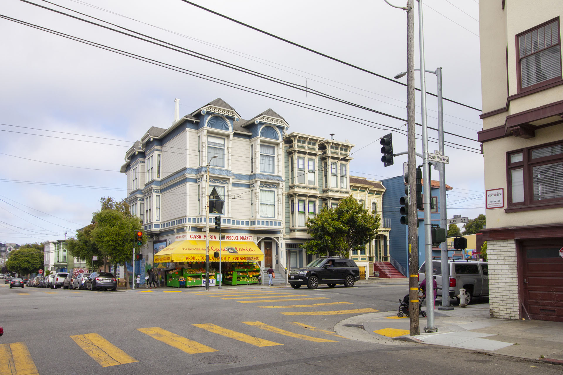 A street view with a building on the left and a car on the road.