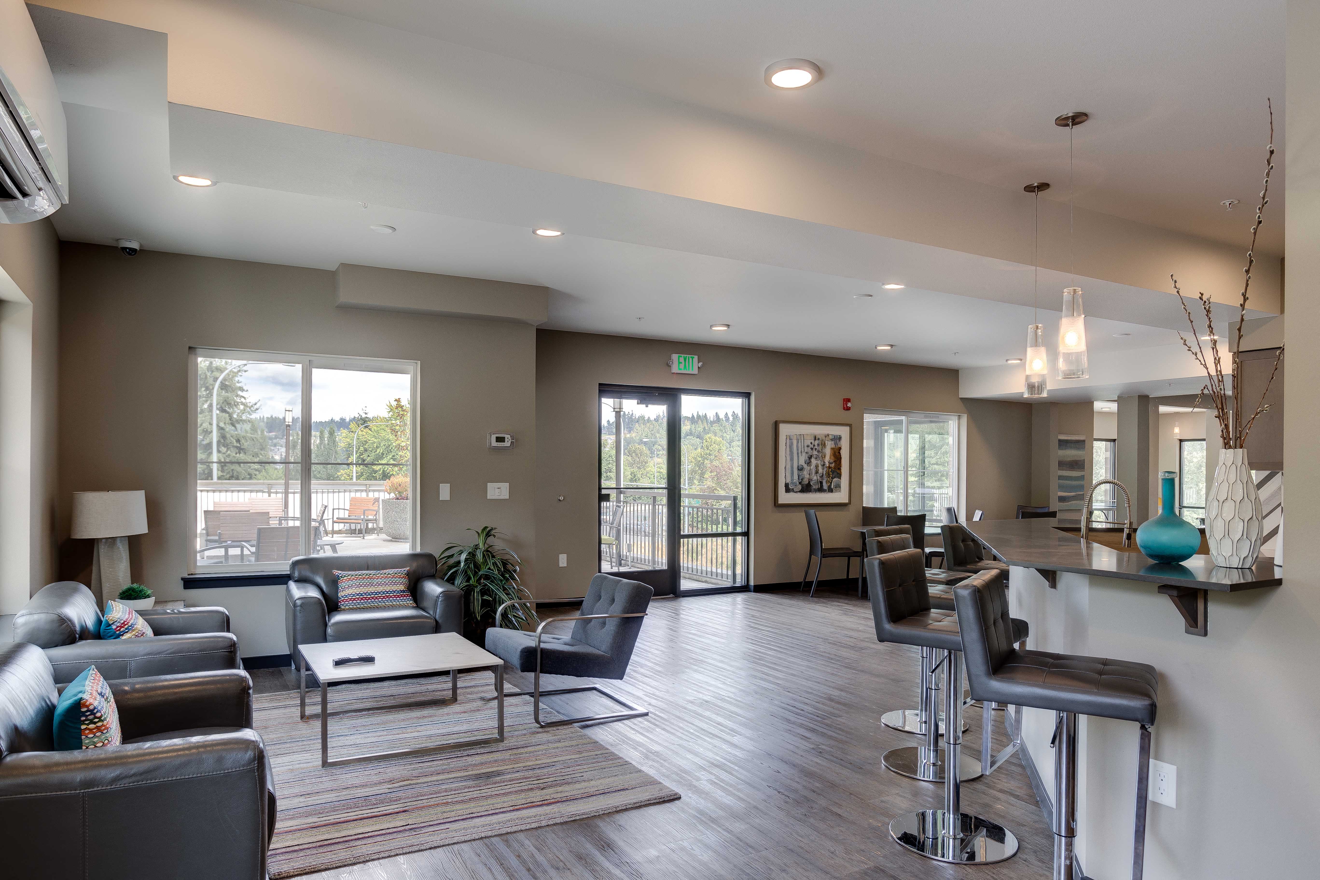 a community room with couches and chairs and a bar and glass doors
