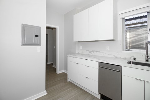 A white kitchen with a dishwasher and a window.