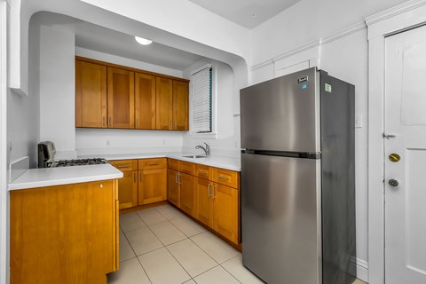 A kitchen with a stainless steel refrigerator and wooden cabinets.