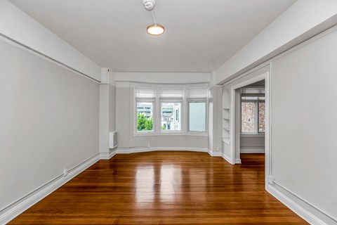 an empty living room with wood floors and a bay window