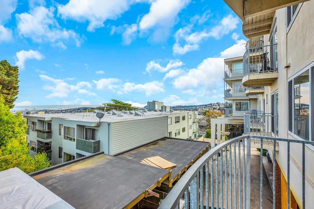 A balcony overlooks a courtyard with a building in the background.