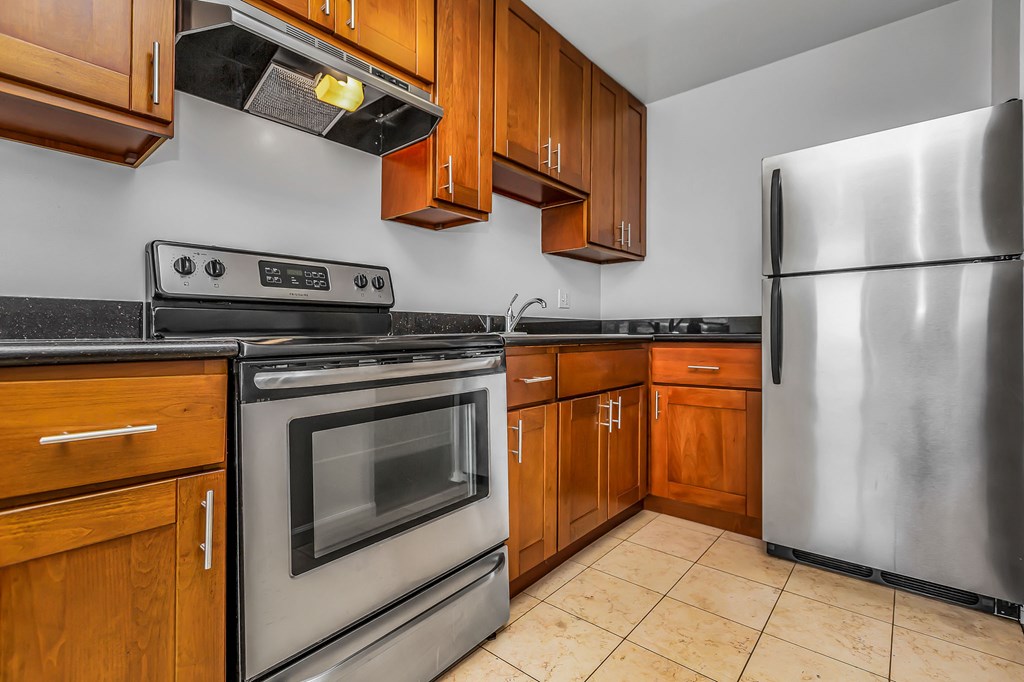 A kitchen with wooden cabinets and a stainless steel refrigerator.
