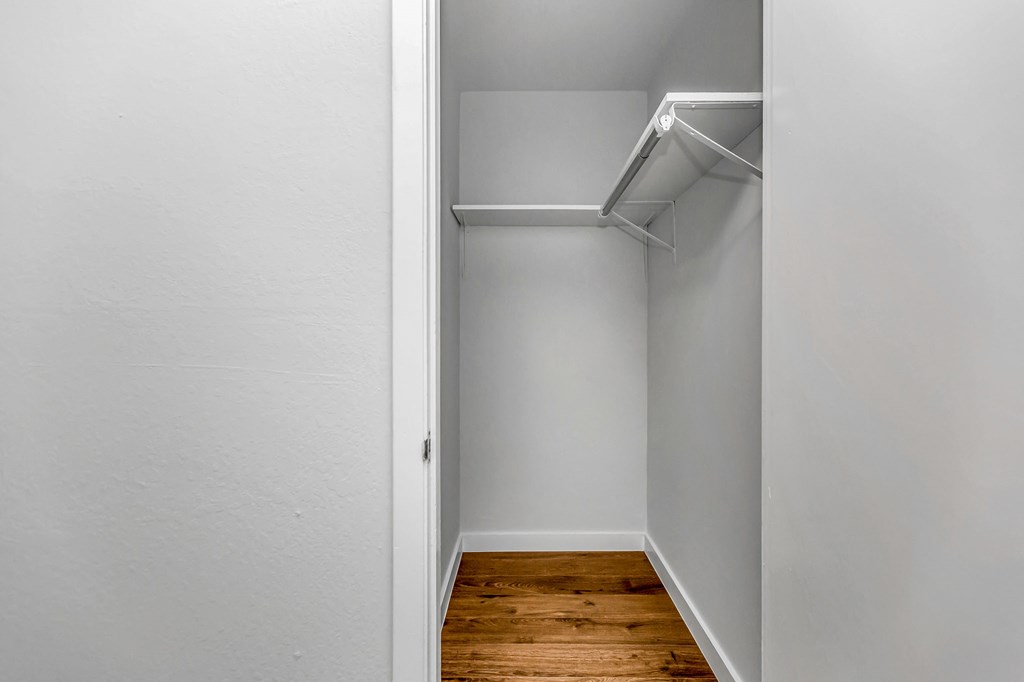 A white closet with a shelf and a door.
