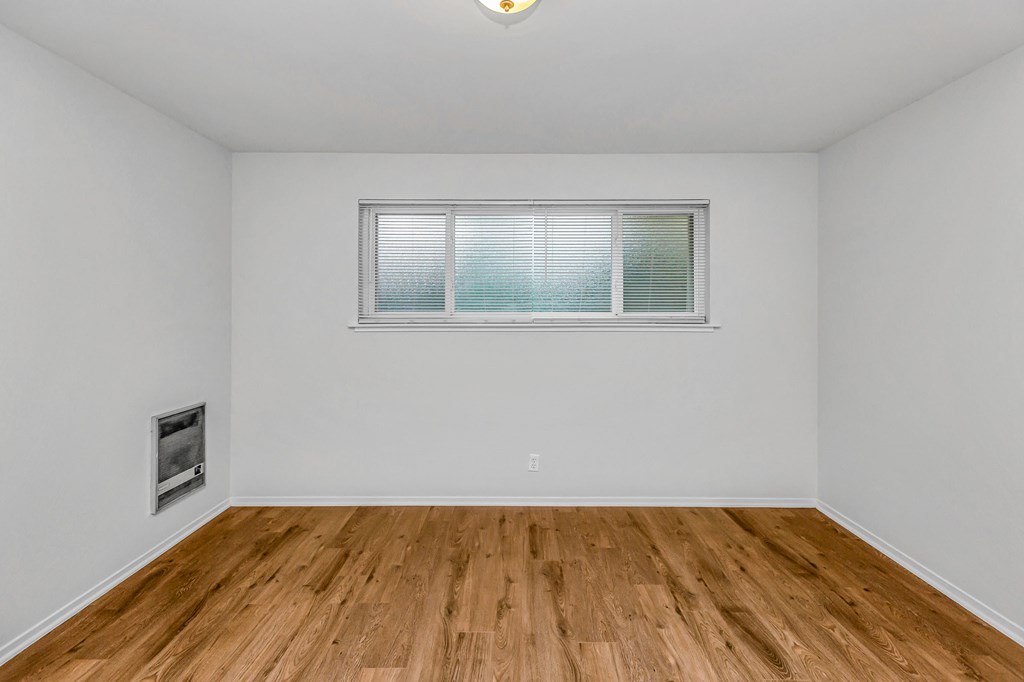 A room with a window and a wooden floor.