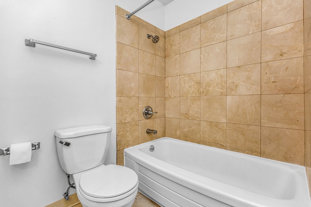 A bathroom with a toilet, a bathtub, and a towel rack.