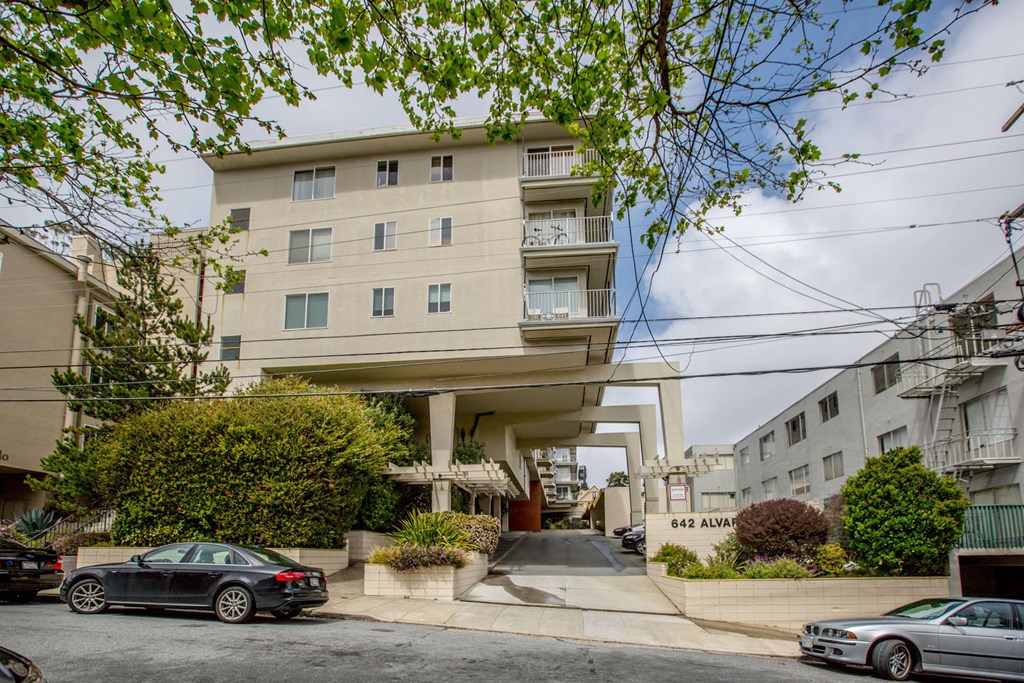 A black car is parked in front of a building with the number 842 on it.