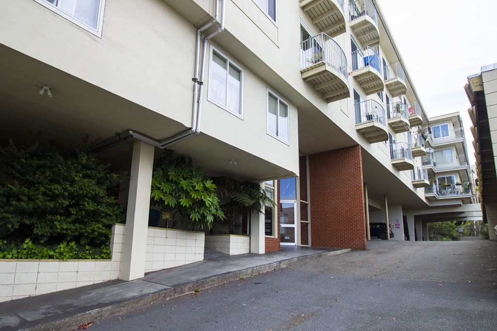 A long white building with a balcony on the top floor.