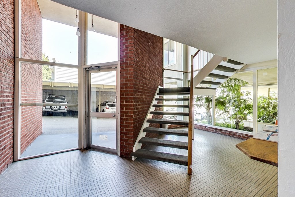 A view of a hallway with a brick wall and a staircase.