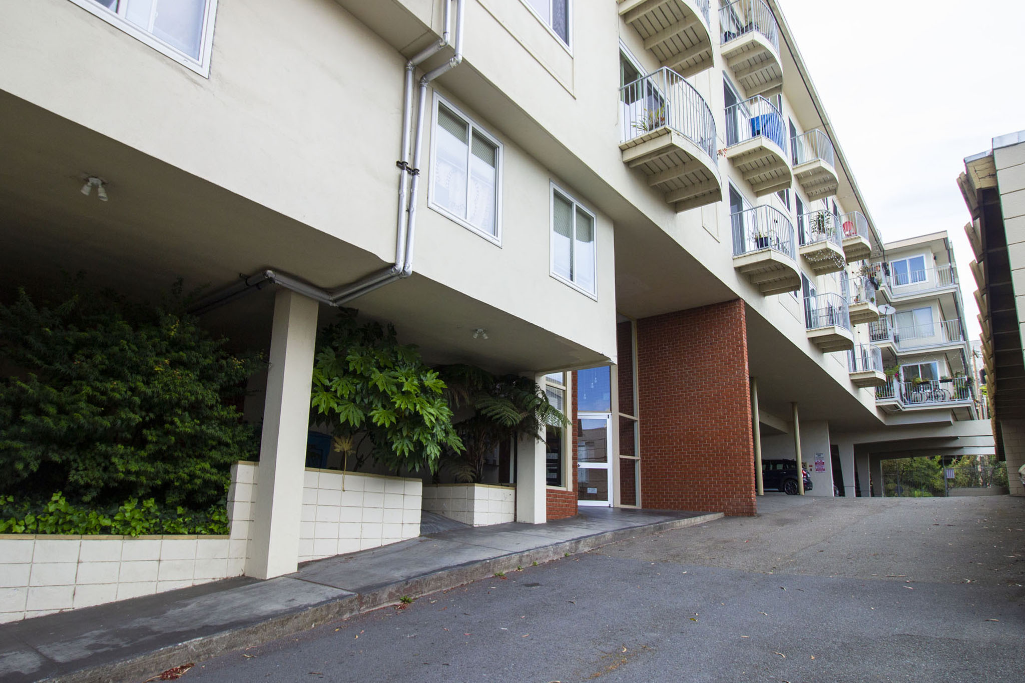 A long white building with balconies and a brown door.