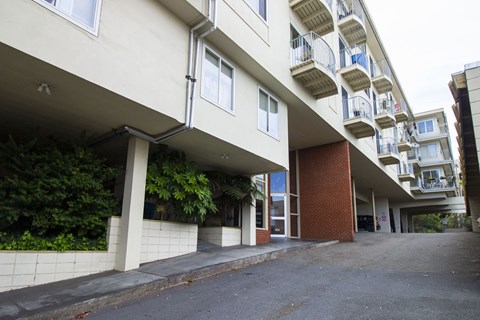 A long white building with balconies and a brown door.