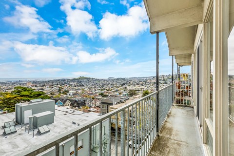 A balcony overlooks a cityscape on a sunny day.