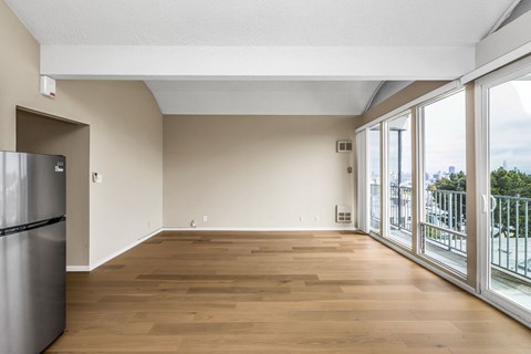 A kitchen with a refrigerator and wooden floors.