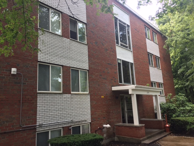 A red brick building with a white framed window on the second floor.