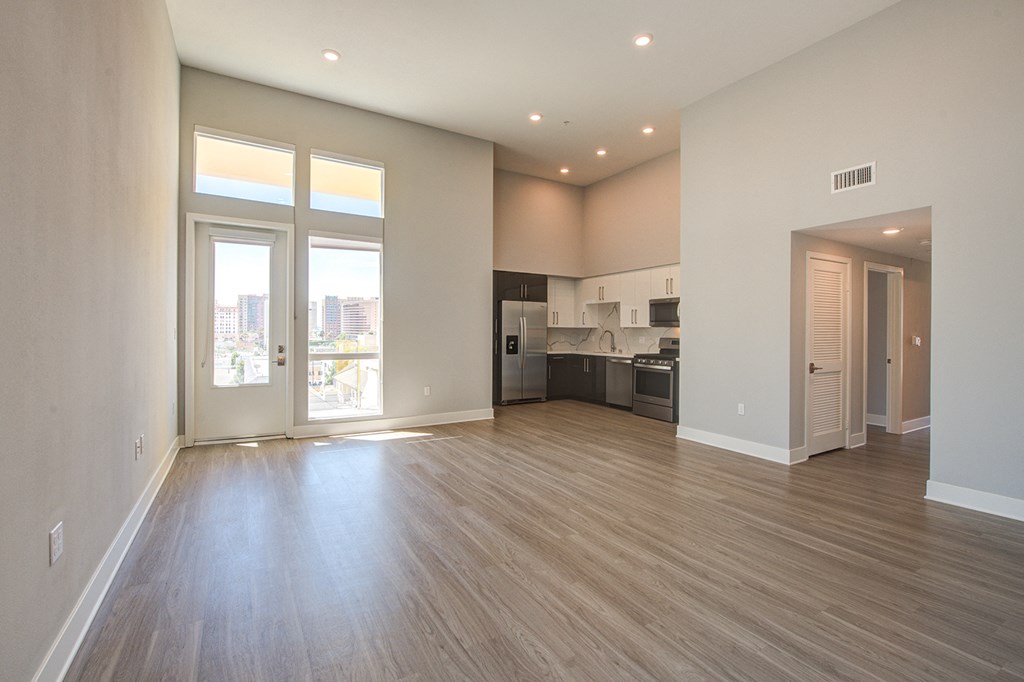 an empty living room with a large window and a kitchen