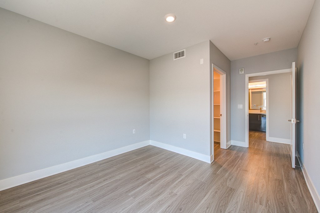 an empty living room with wood flooring and a door to a bathroom