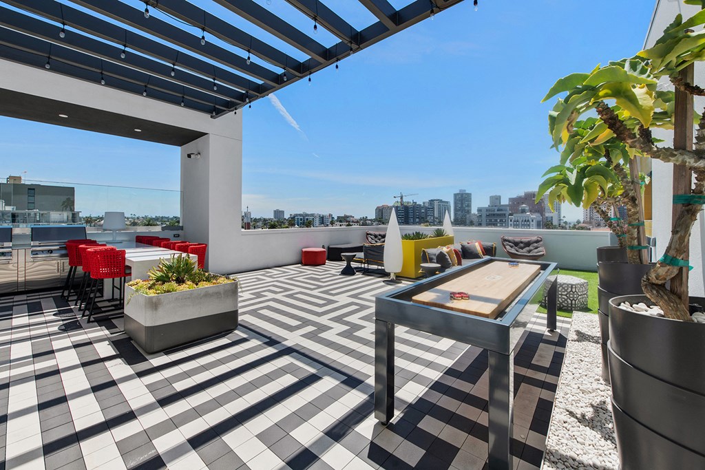 a rooftop patio with a table and chairs and a city in the background