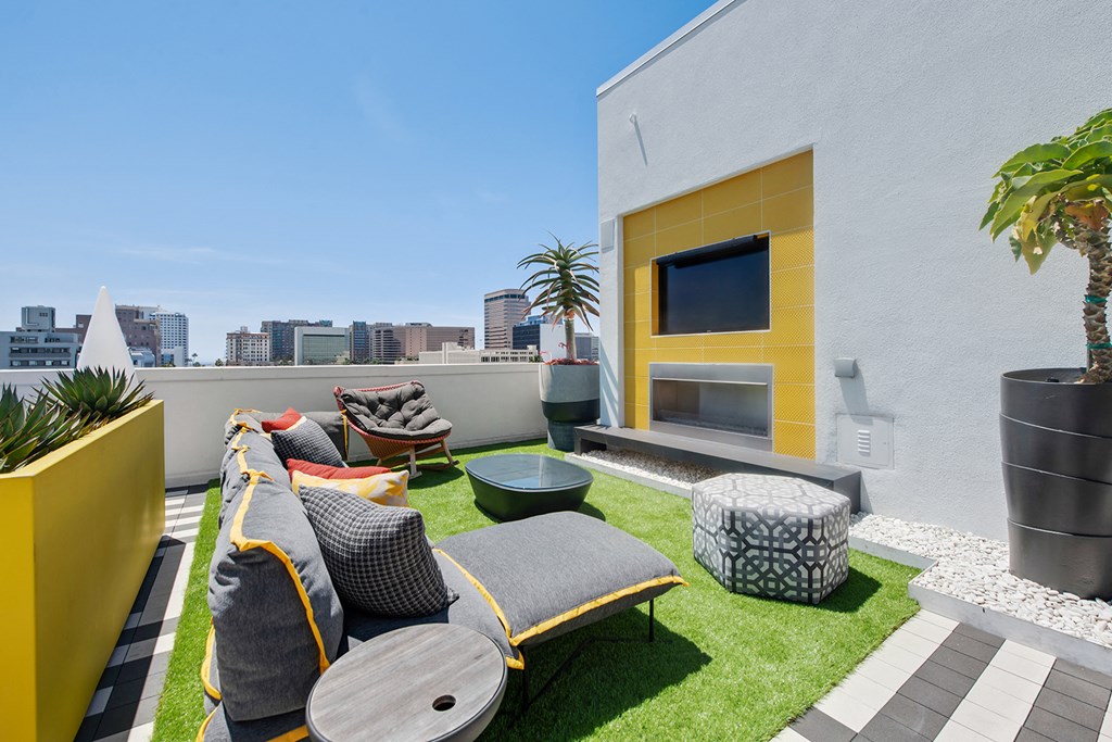 a roof top patio with couches and chairs and grass