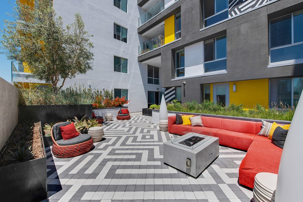 a living area with couches and a fire pit in front of an apartment building