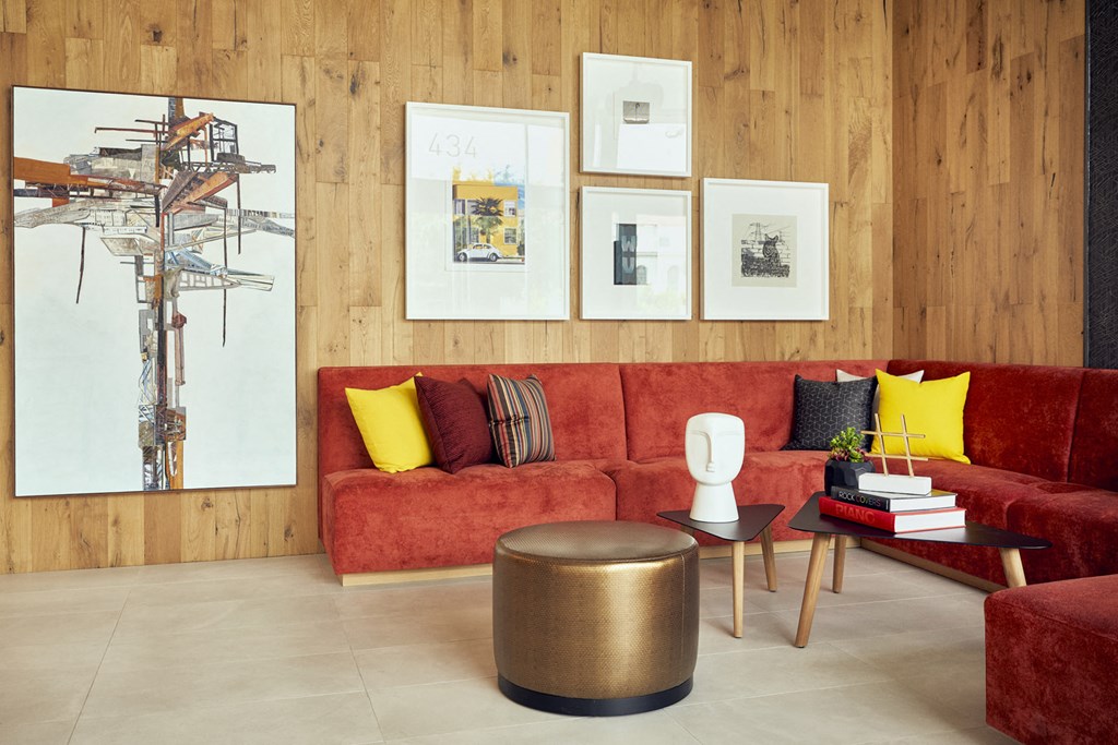 a living room with a red couch and paintings on the wall