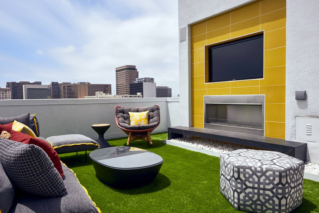a rooftop lounge area with couches and chairs and a fireplace and a city skyline