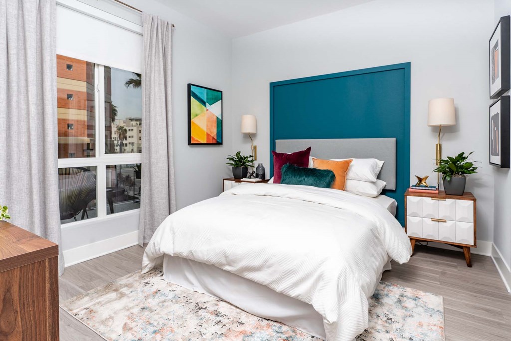 a bedroom with a bed and a blue wall and a window