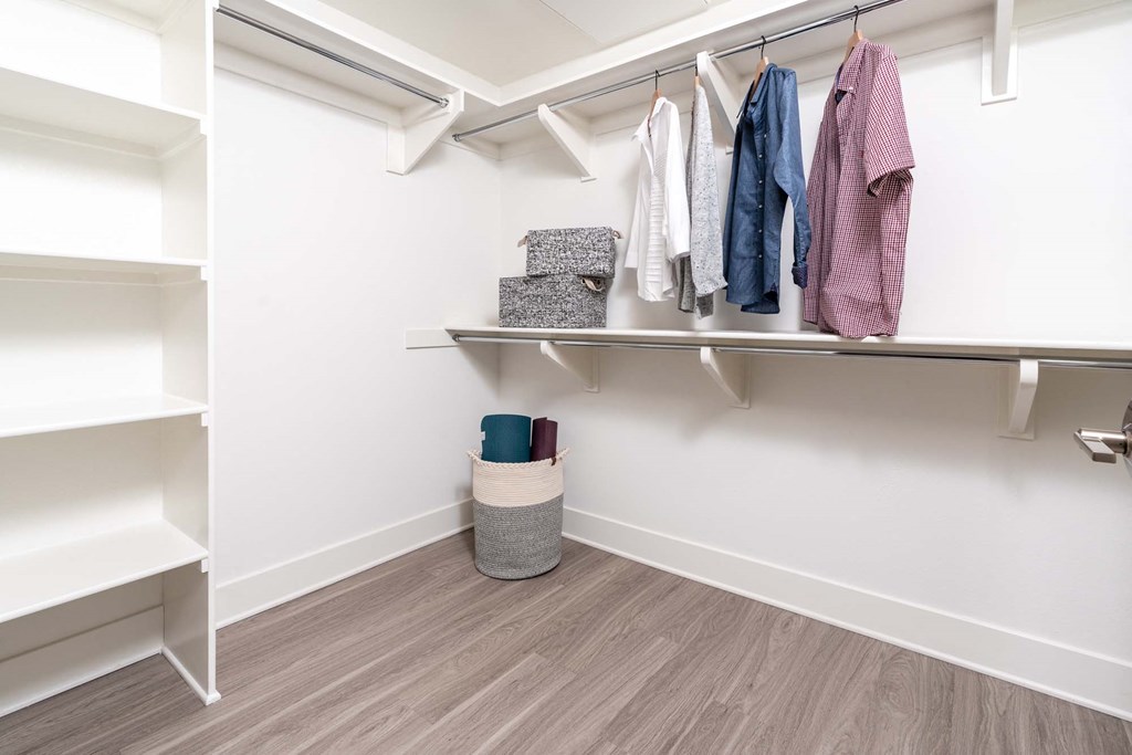 a closet with shelves and clothes hanging on the wall