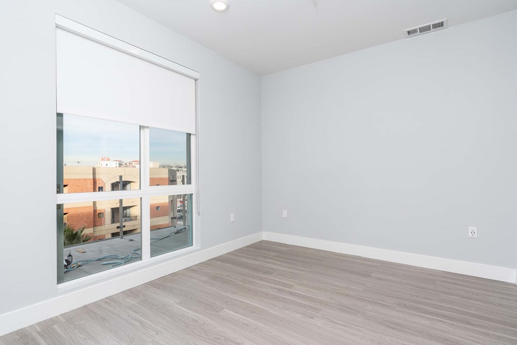 an empty living room with a large window and wood floors