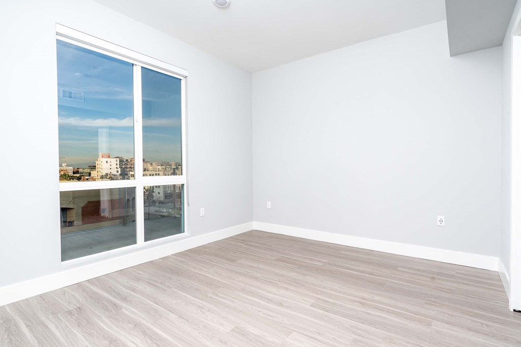 an empty room with a large window and wooden floors