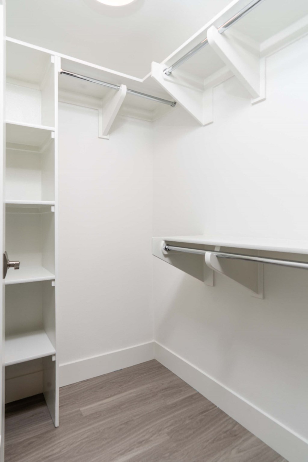 a walk in closet with white walls and shelves