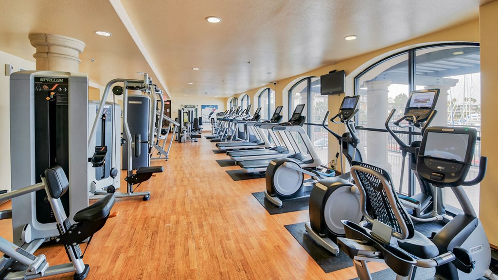 a gym with cardio equipment and weights on a wood floor
